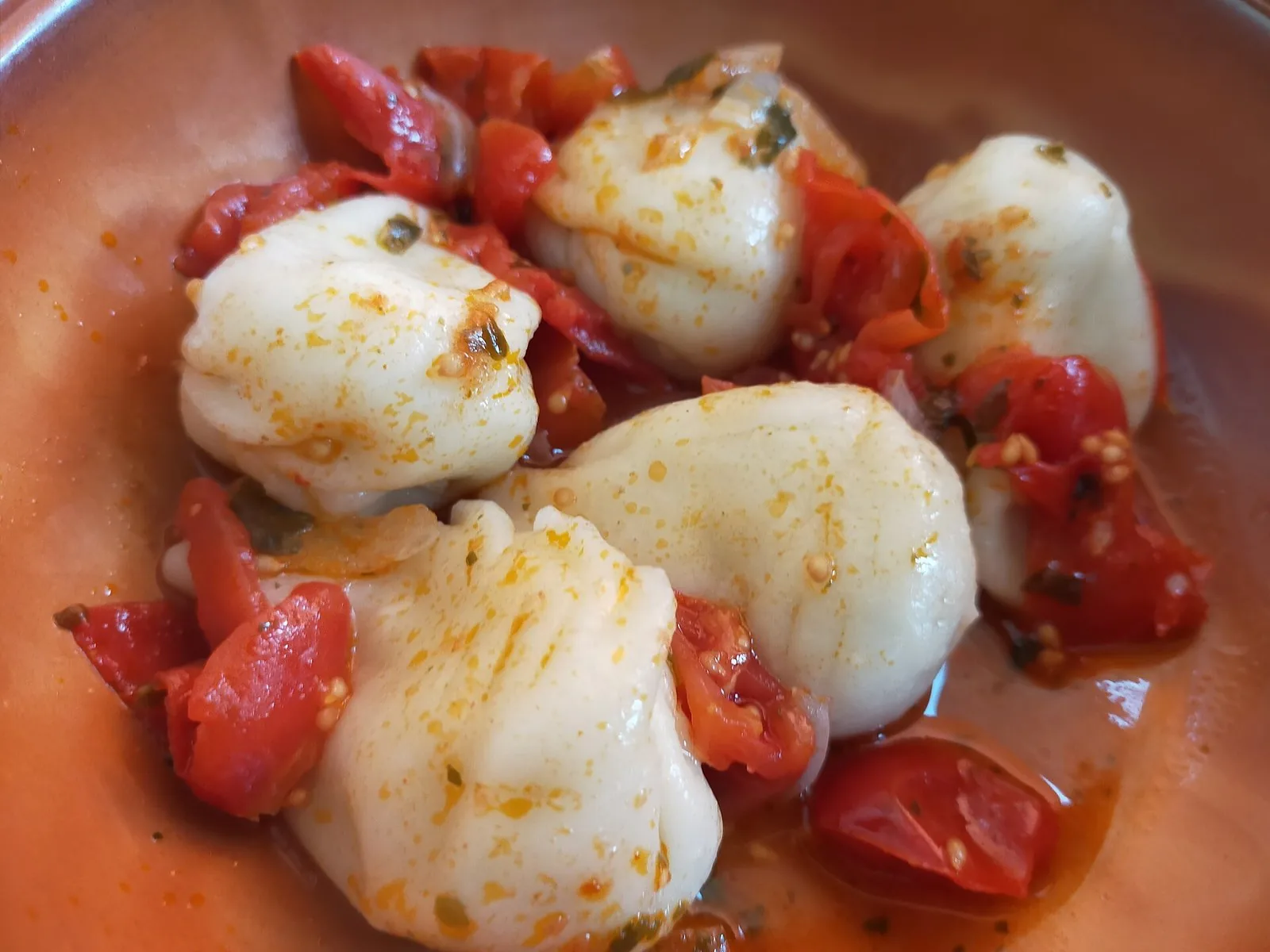 Un piatto di culurgiones conditi con pomodoro fresco